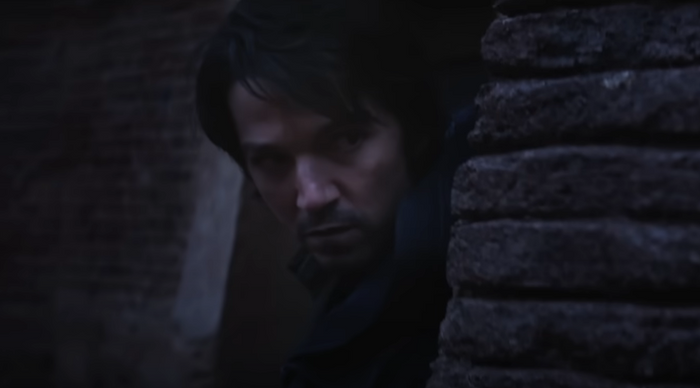 Andor Season 1 Diego Luna as Cassian Andor peeking behind stone wall