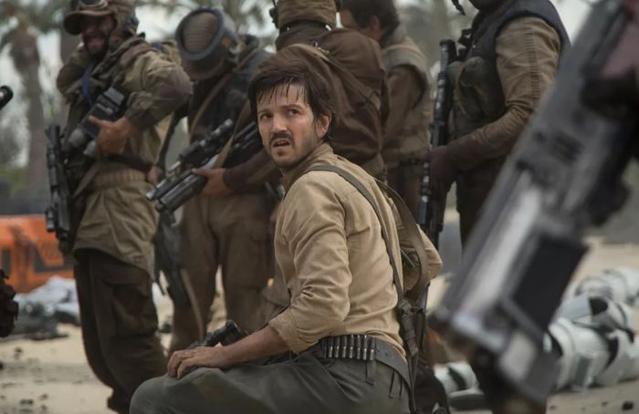 Andor Season 1 Diego Luna as Cassian Andor kneels down and looks back to the camera with soldiers in front of him