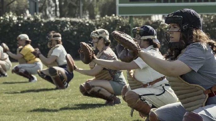 A League of Their Own show cast wearing their baseball uniform playing baseball