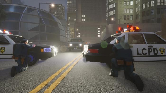 In a city at night, two police cruisers have set up a blockade. Two police officers crouch behind the cars, looking at a van, whose headlights are shining on them.
