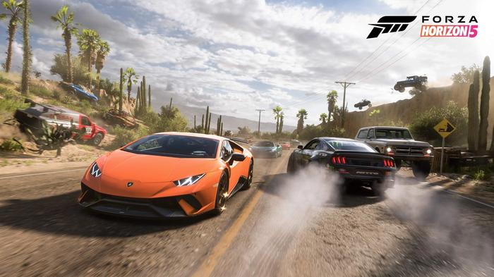 An orange Lamborghini heads towards you along a dusty road, with cars behind it. Other cars are driving along hills.