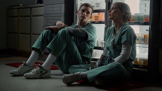 Jessica Chastain as Amy Loughren, Eddie Redmayne as Charlie Cullen in The Good Nurse sitting on the floor against vending machine
