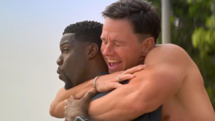 Me Time shirtless Mark Wahlberg as Huck hugs shocked Kevin Hart as Sonny from the back