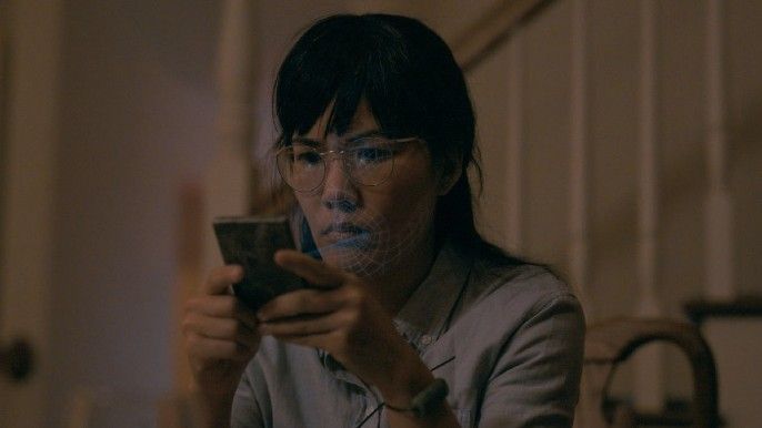 Paper Girls cast Ali Wong as an adult Erin sits on bed and looks at phone