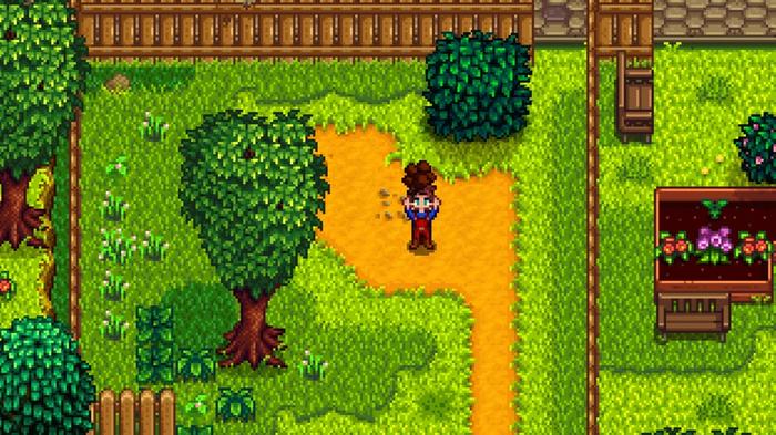 Stardew Valley. The player is holding up a piece of Clay above their head. They're standing on dry soil and there are pieces of grass surrounding them.