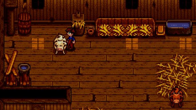 Stardew Valley. The player is inside the Barn with a White Cow. The player is facing the white cow on their left. The barn is made out of brown wood and there are pieces of Hay scattered around.