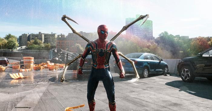 Spider-Man stands on a bridge with all four arms of his spider suit sticking out.