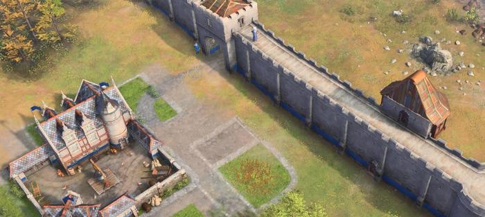 A village with defensive stone walls and towers in Age of Empires 4.