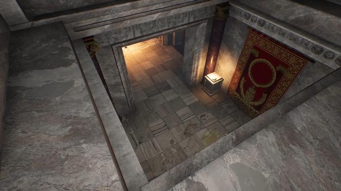 The Forgotten City. The image shows the view from an upper level where the player can drop down into the next room. There is a gold and red tapestry to the right of the room and a flame-lit torch. 