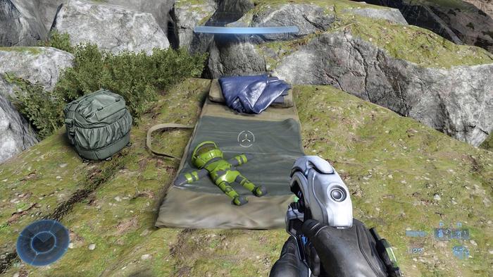 A small Master Chief doll is seen on top of a camping mat on a hill.