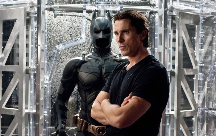 Christian Bale standing in front of his Batman Batsuit.