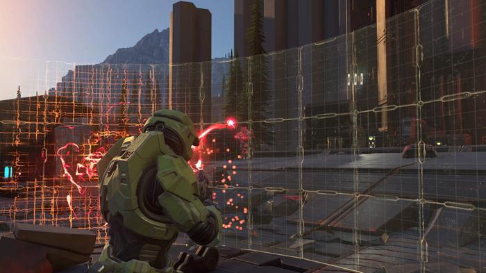 Halo Infinite's Master Chief shoots enemies from behind a shield.