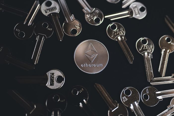 Ethereum silver coin on black surface surrounded by keys.