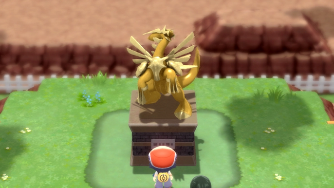 A Pokémon Trainer standing in front of the Dialga legendary statue in Pokémon Brilliant Diamond and Shining Pearl.