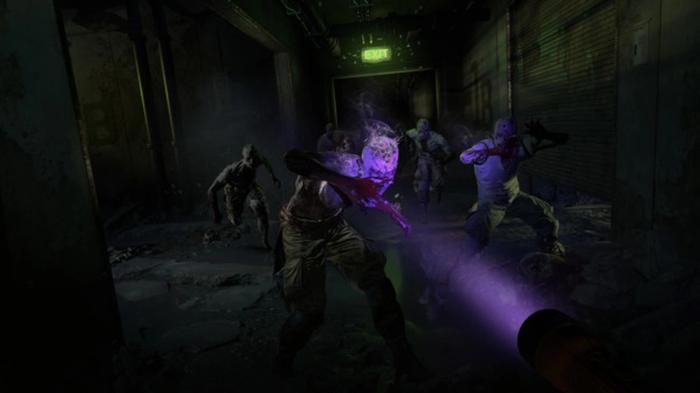Dying Light 2. A dark hall filled with infected monsters. A UV torch is being pointed at them.