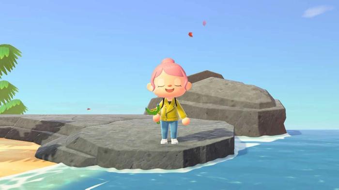 Animal Crossing New Horizons, the player is stood on a rock near the edge of the ocean and they are holding their slingshot. Their eyes are closed.
