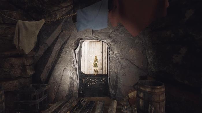 The Forgotten City. A golden statue is blocking a doorway. There are pieces of cloth hanging on the stone wall above the doorway. A torch is lighting up the small doorway and statue.