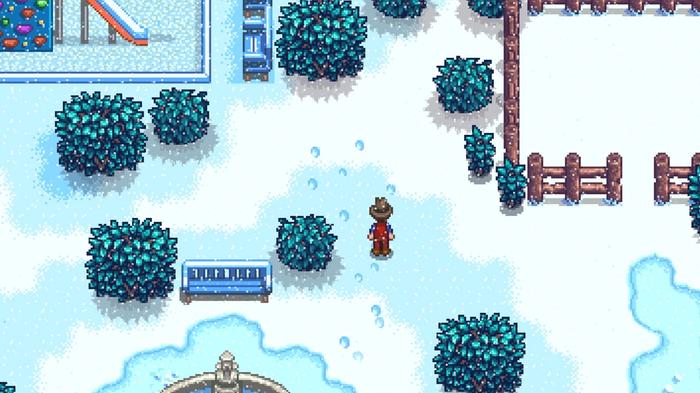 Stardew Valley. Winter Season, the player is following footprints in the snow left by the shadowy figure. They are leading up to the bush to the right of the playground.