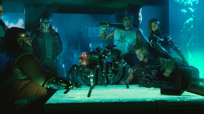 Cyberpunk 2077 Screenshot - several characters sitting in a bar around a table, turquoise lighting, four legged mech on the table.