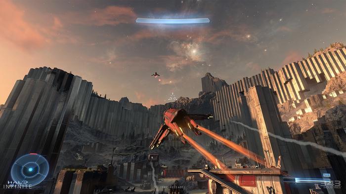 A player flies a Banshee vehicle up and over a ridge on Zeta Halo. The sun is setting in the background