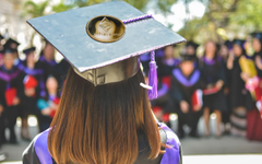 Image of a graduating woman with a graduation cap that features a physical Ethereum coin