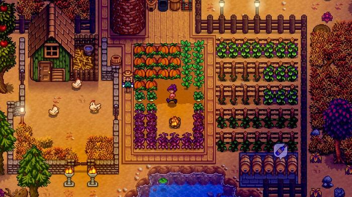 Stardew Valley. The player is stood by their pumpkin patch among their crops in the evening. There is a wildlife barn to the left of the image. To the right of the image there are sections of crops that are ready to be harvested.