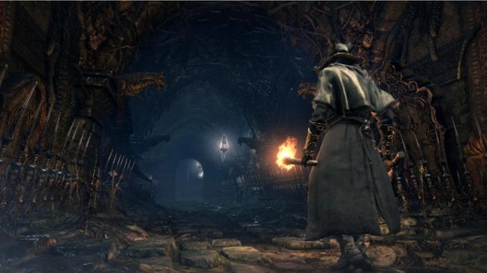 A character walking down a dark cave in Bloodborne.