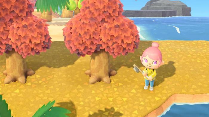 Animal Crossing New Horizons, the player is standing next to a tree while holding a flimsy axe. It's autumn. The player is on the right and wearing a yellow jacket with blue trousers.