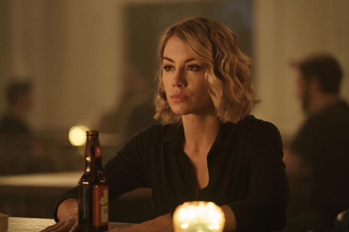 Harcourt sits in a bar with a beer bottle in front of her.