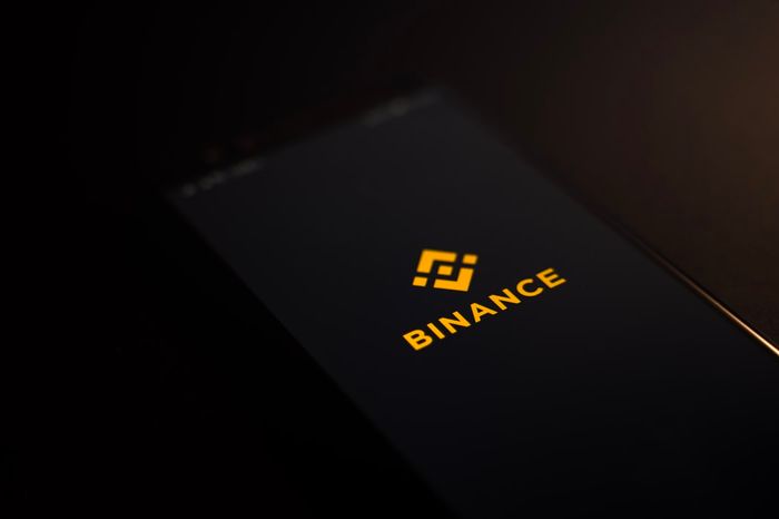 Binance logo on a phone on a dark background.
