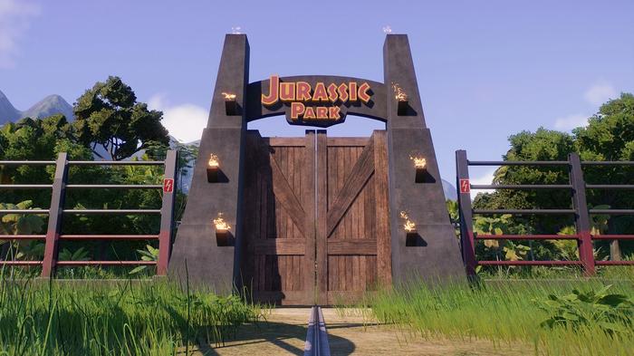 Jurassic World Evolution 2. The image is showing the entrance gates to the 1993 movie Jurassic Park and the gate is connected to electric fences on either side. 