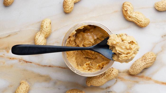 Peanut butter surrounded by peanuts on a black spoon.