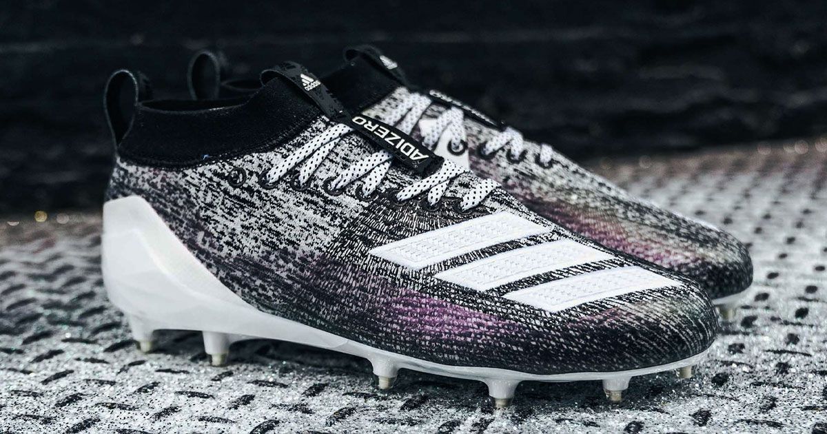 A pair of black and white knitted adidas football cleats with purple details.