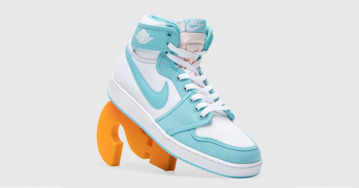 A white leather and light blue canvas Air Jordan 1 leaning against an orange question mark.