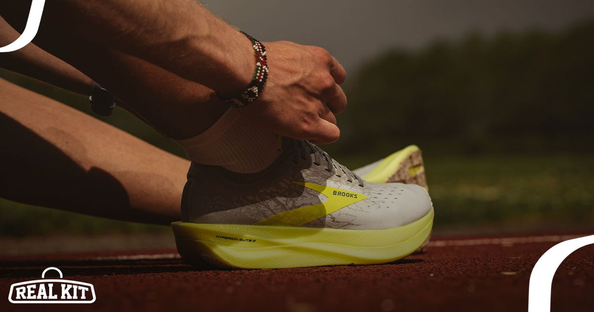 A person tying up a grey and yellow running shoe while sat on a running track.