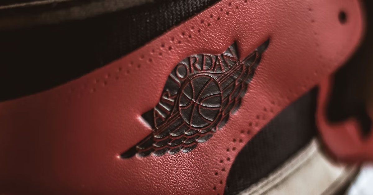 A black Air Jordan wings logo embossed onto a red leather sneaker.