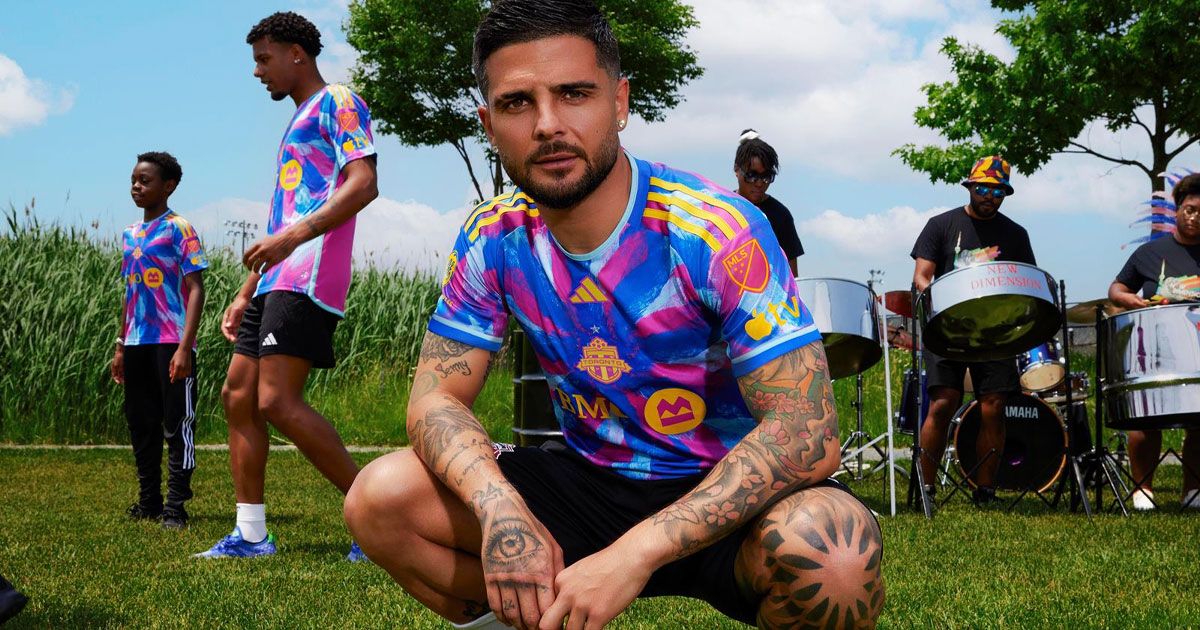 Insigne wearing a pink and two-tone blue shirt with yellow trim and branding.