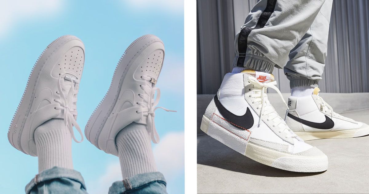 Someone in blue jeans wearing all-white Air Force 1 Lows on the left. On the right, someone wearing white Nike Blazer Mids featuring black Swooshes.