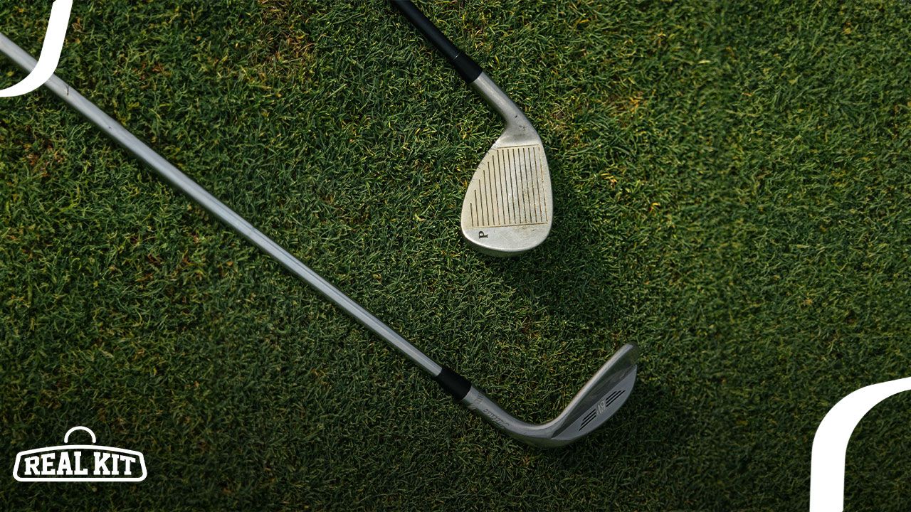 Two silver and black iron golf clubs laying on grass.