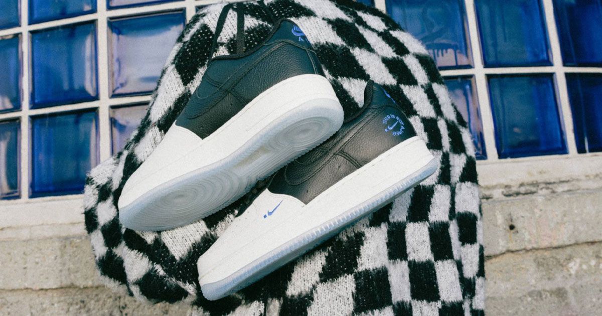Someone in a white and black fluffy chequered jumper holding a two-tone pair of white and black Air Force 1 Lows over their shoulder.
