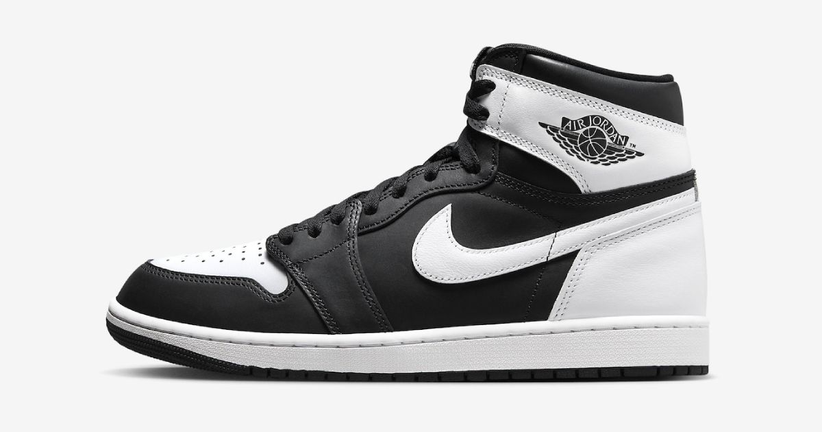 A black and white Air Jordan 1 high-top with a white Swoosh down the sidewall.