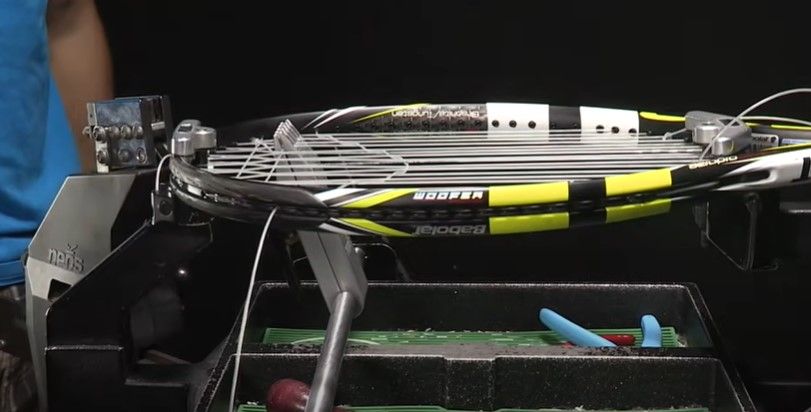 Image of a black, yellow, and white Babolat tennis racquet with cross strings tightened over main strings.
