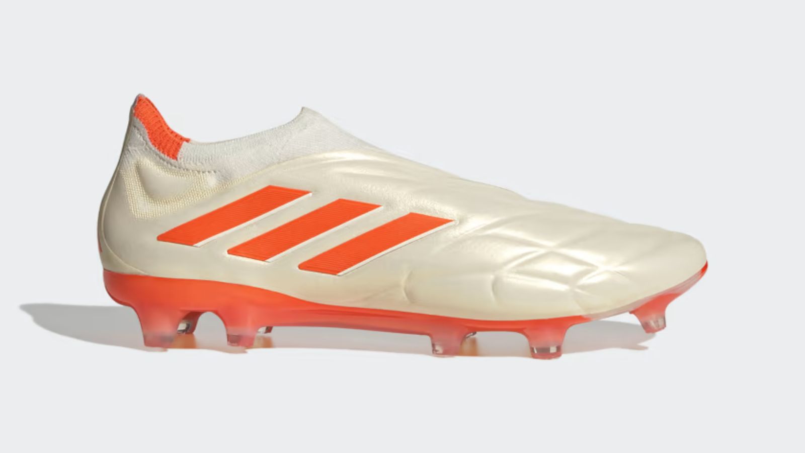 adidas Copa Pure+ product image of an off-white football boot featuring bright orange accents.