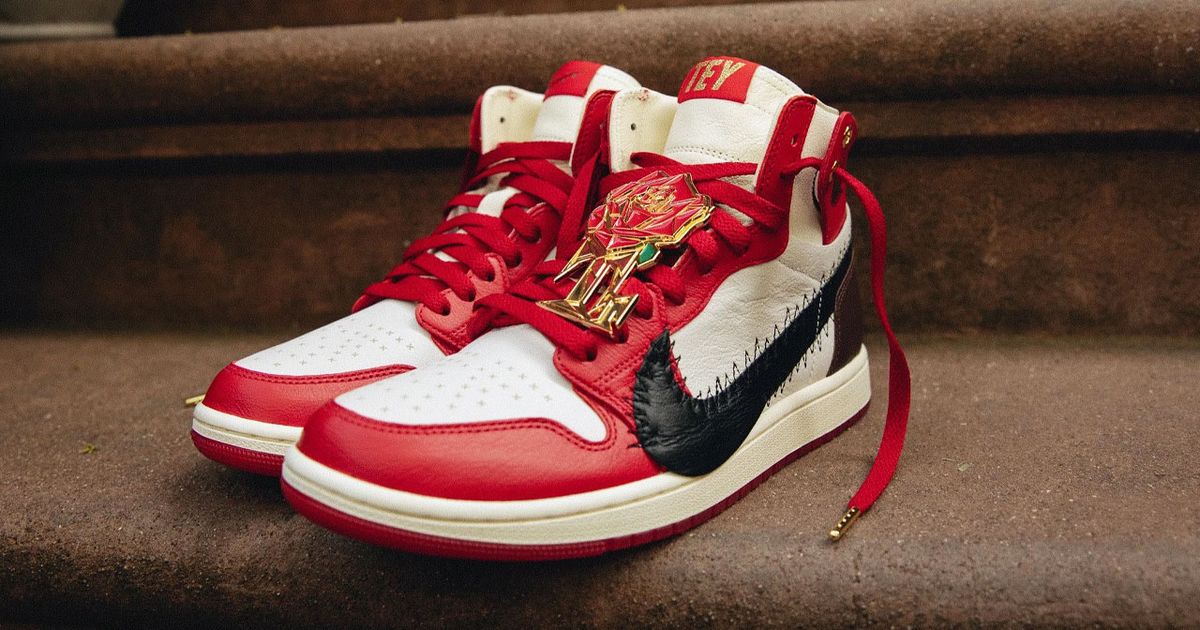 A red and white high-top Jordan 1 featuring red laces and an oversized black Swoosh down the side.