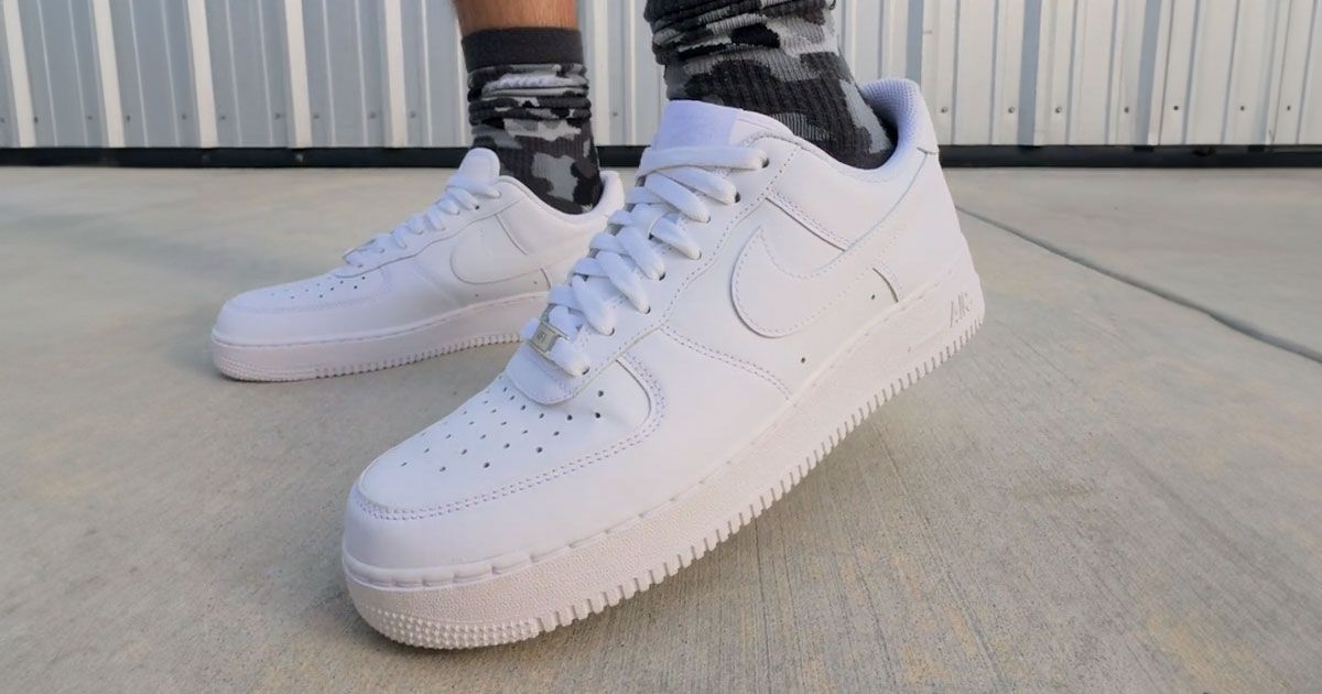 Someone in black and white camo socks wearing a pair of all-white Nike Air Force 1 Lows.