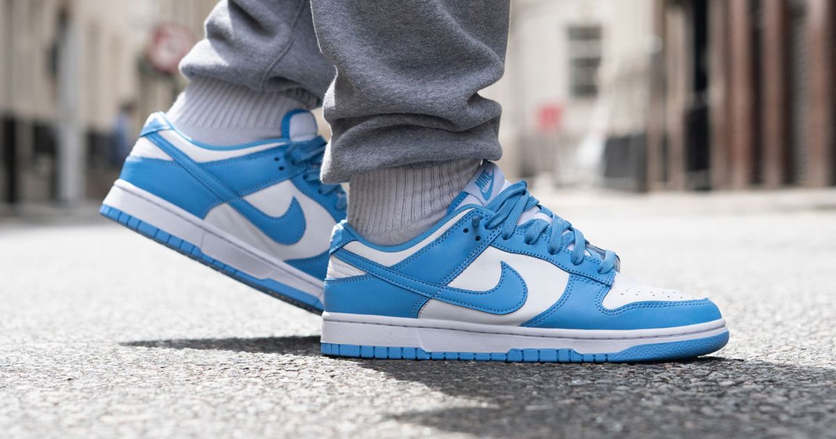 Someone in grey joggers and white socks wearing a pair of light blue and white Nike Dunk Lows.