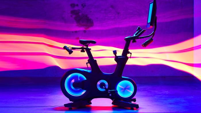 Latest exercise bike news Echelon product image a dark-framed bike with blue LED lights around the wheels.