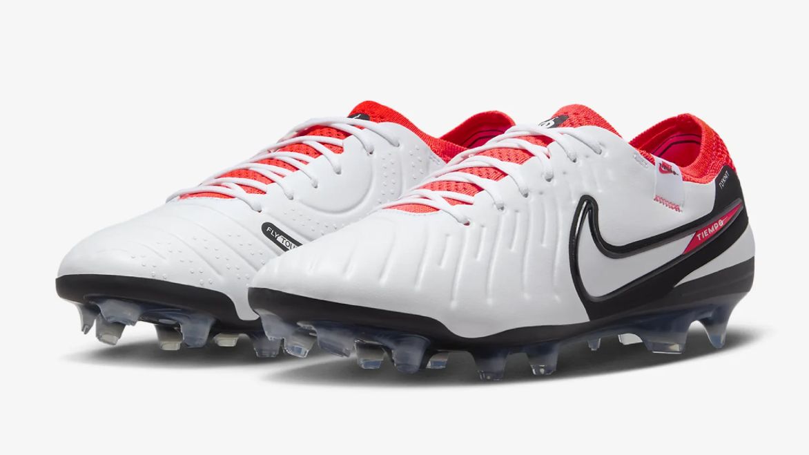 A pair of white Nike football boots featuring red lining and Swooshes with black outlines down the sides.