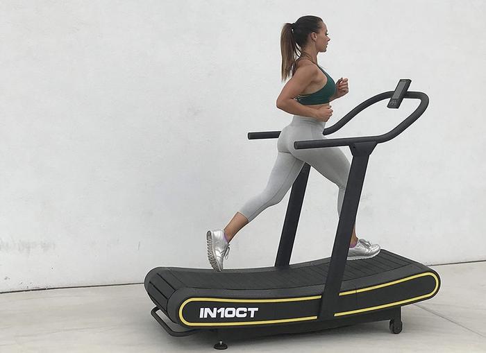 the best treadmill curved. Curved treadmill product image with lady running on it.