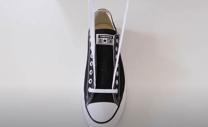Converse product image of a black sneaker with white laces tightened through the first eyelets.